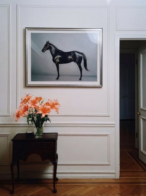Paneled room with a framed horse painting and orange lilies