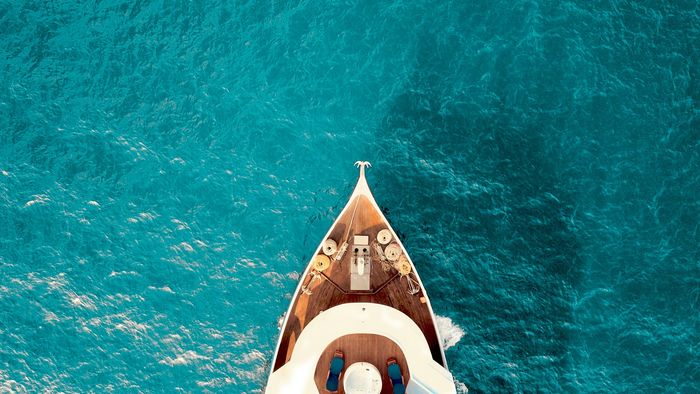 Aerial of a yacht bow cutting through turquoise water