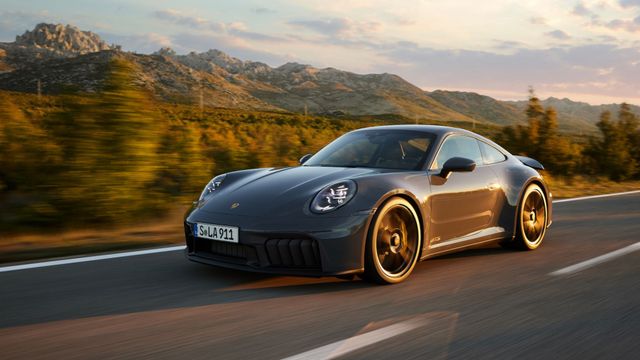 A Porsche 911 GTS at speed on a mountain road at dusk